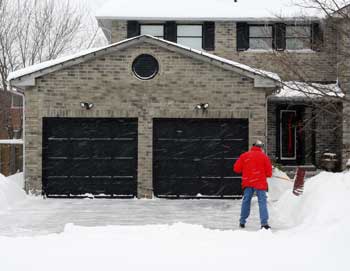 Man shoveling snow in front of 2-car garage - Feature image