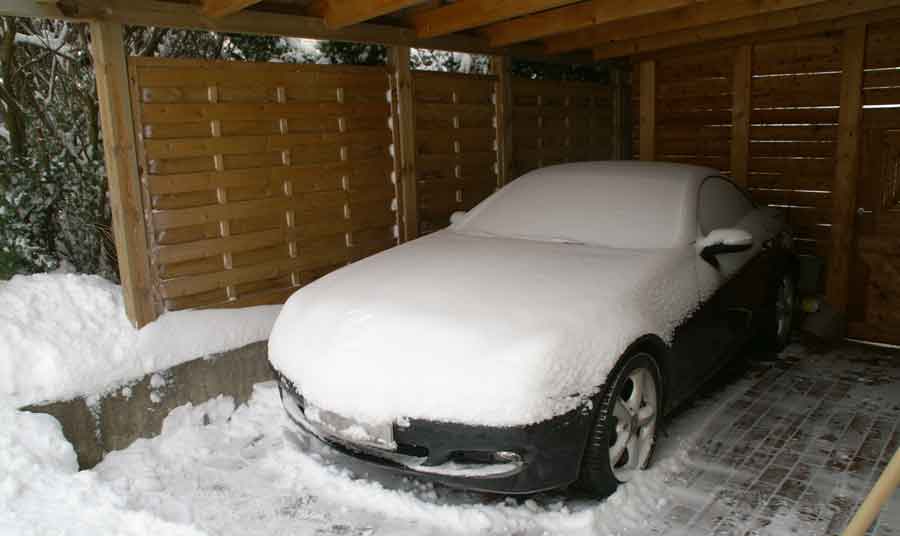 Snow covered car in carport