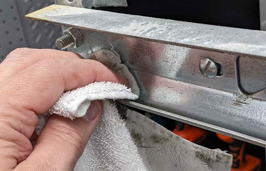 using a cloth to clean garage door tracks
