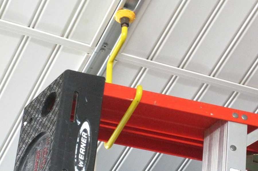 Overhead storage hook holding a ladder