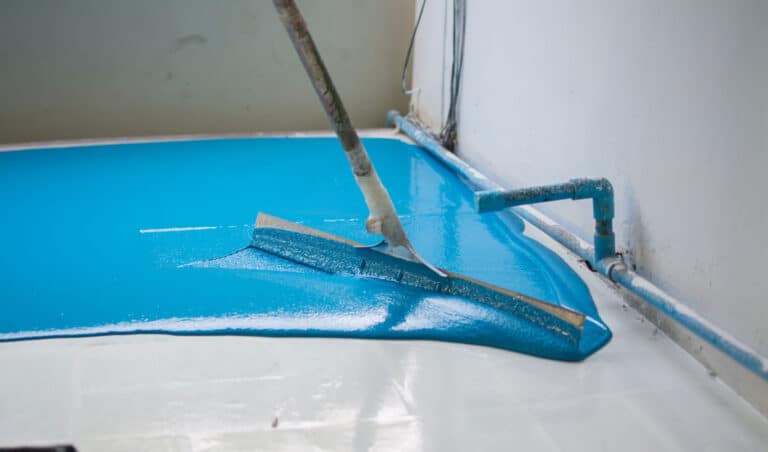 Flooring contractor spreading blue epoxy on garage floor