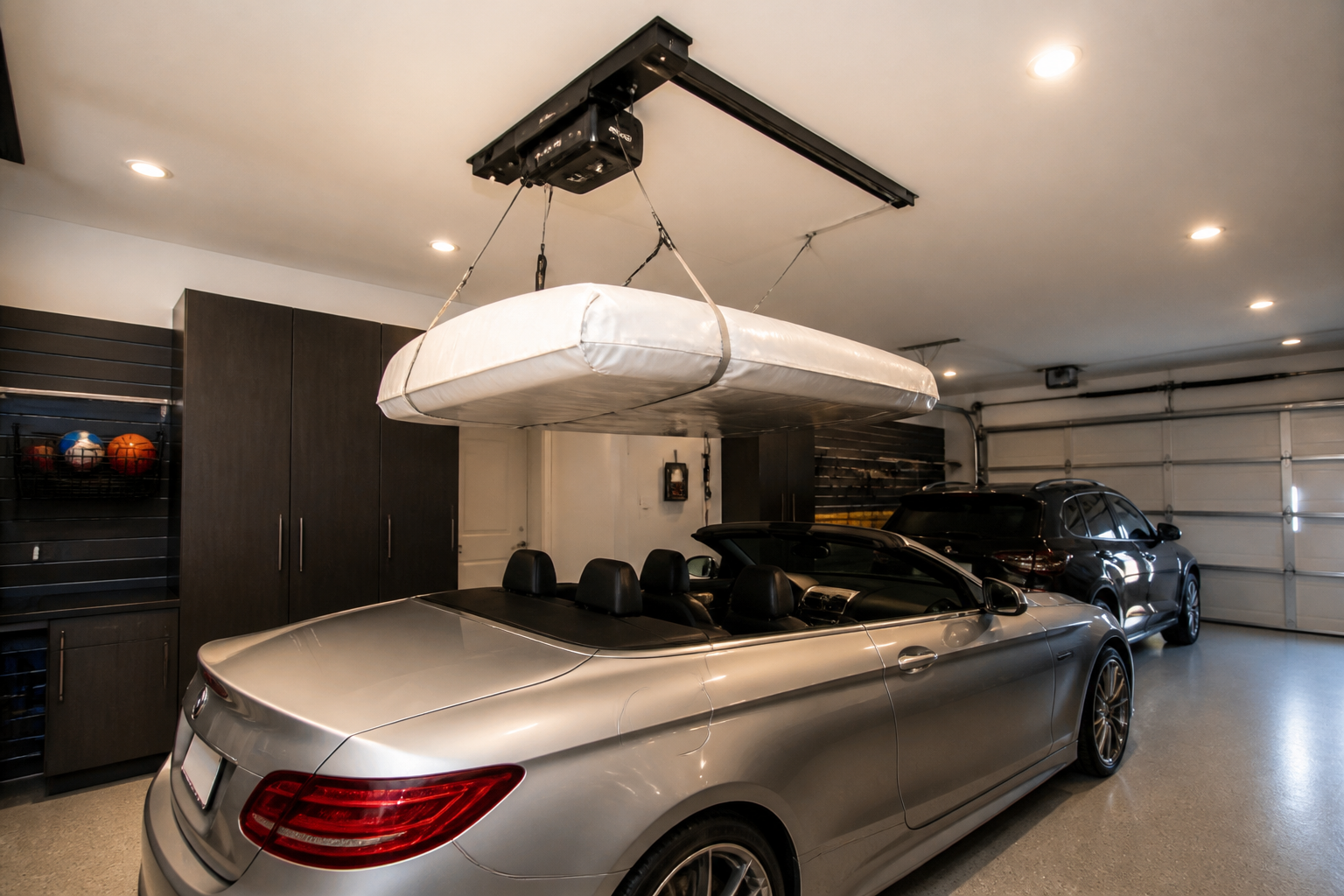 Electric ceiling hoist with remote control lifting wrapped convertible hardtop panel to storage position