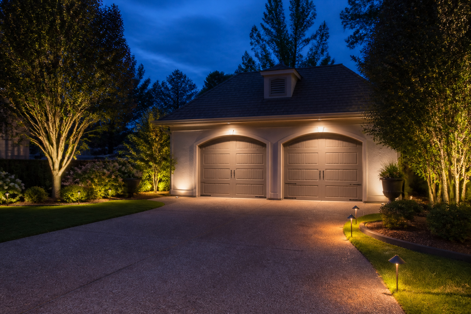 Garage with integrated lighting illuminating surrounding trees and pathway for cohesive design