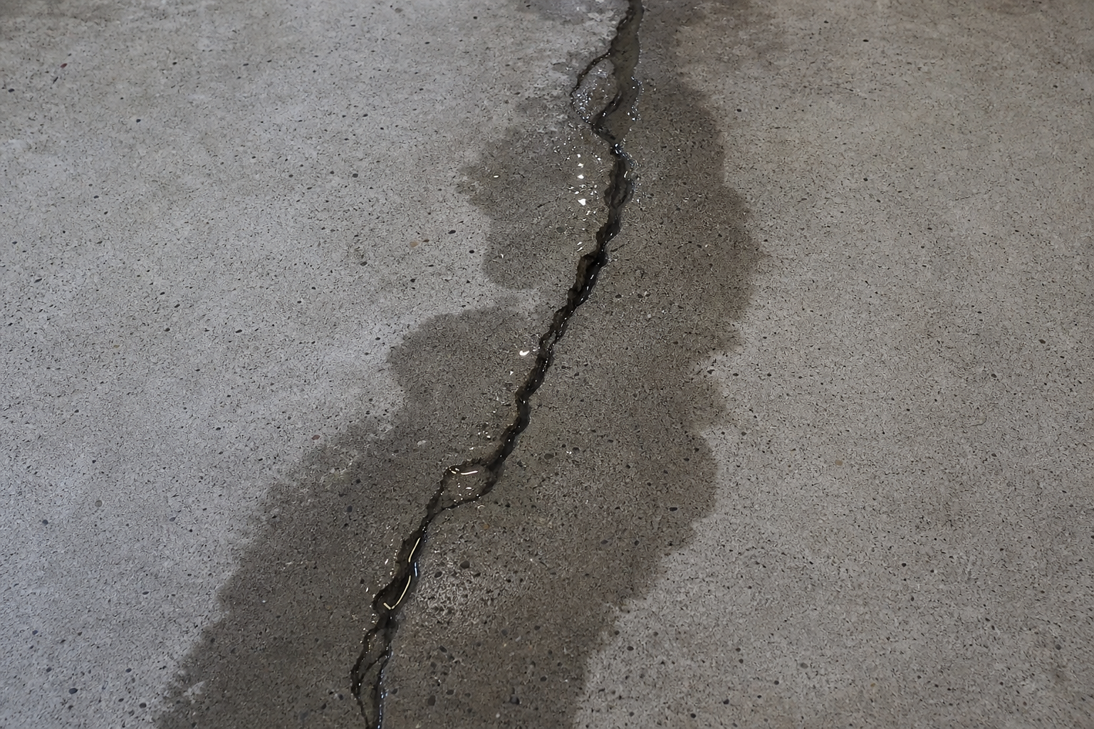 Close-up of concrete garage floor crack with visible water seepage