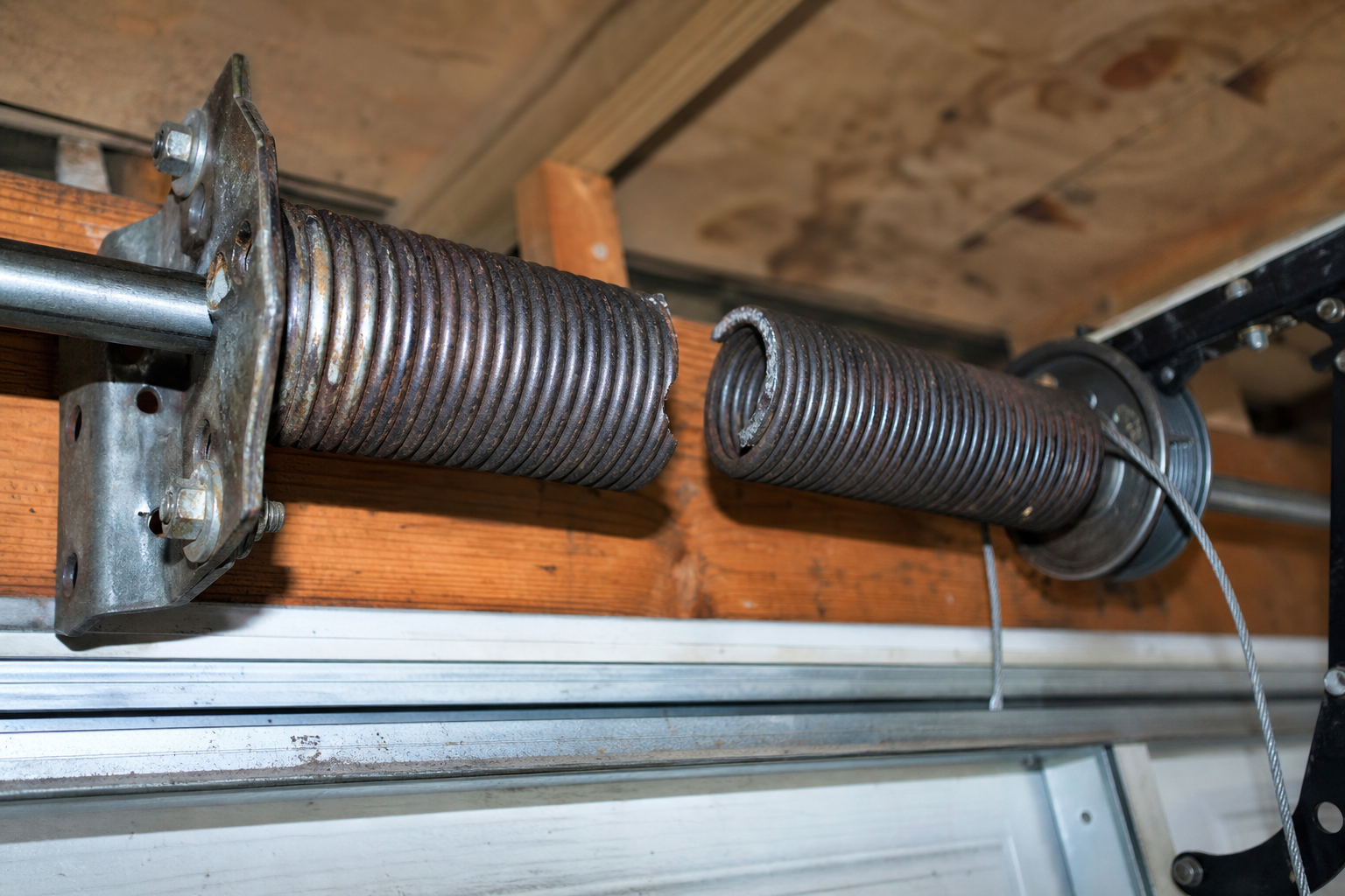 Broken garage door torsion spring showing visible fracture in metal coil