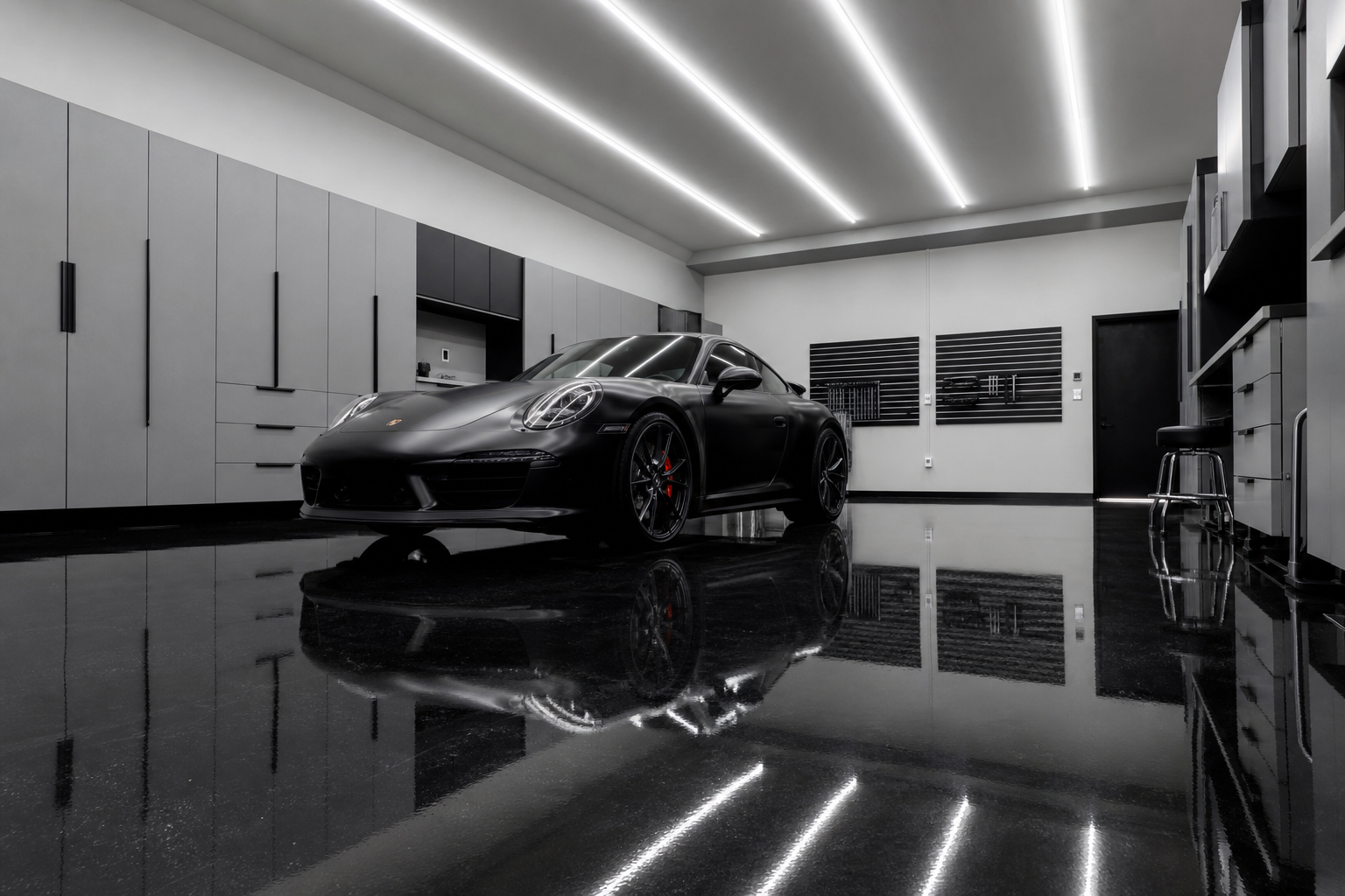 High-gloss solid black epoxy garage floor with sports car reflection and bright LED ceiling lights