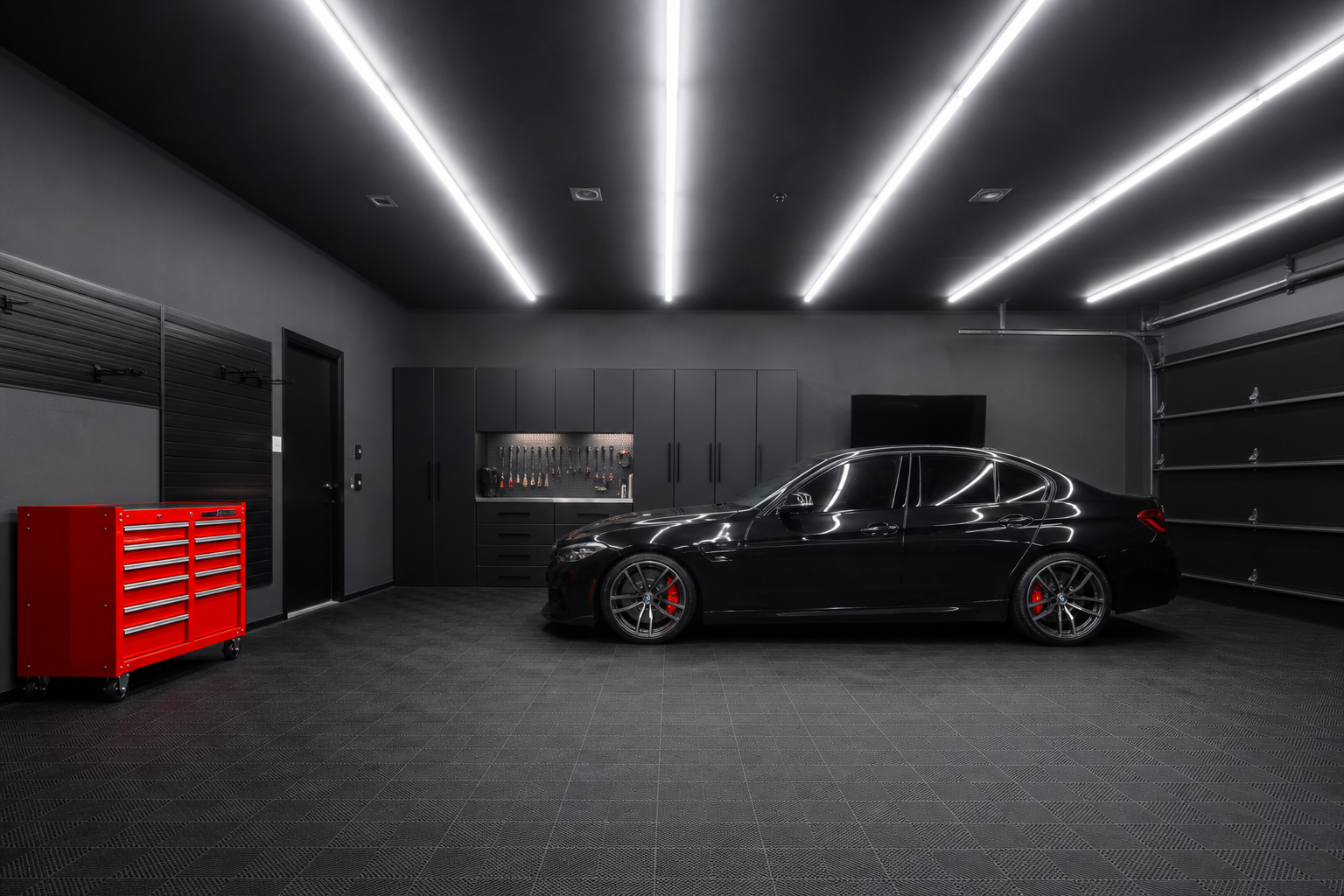 High-output white LED shop lights on black ceiling with dark charcoal walls and black tile garage floor