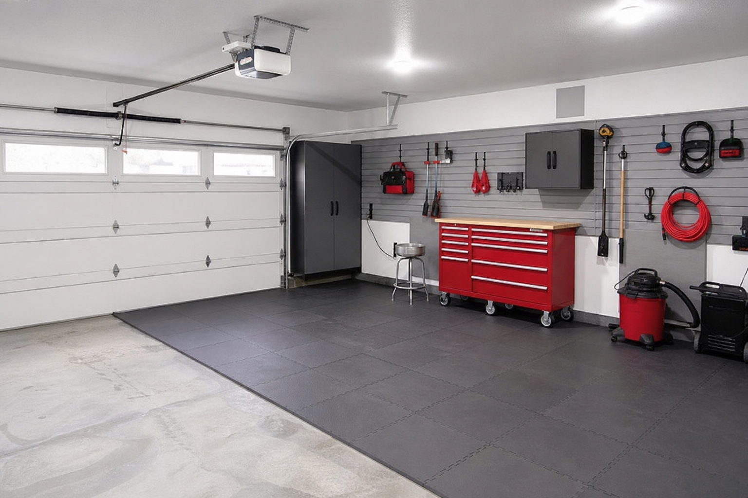 Dark gray foam puzzle mat flooring covering the workshop area of a garage with tool chest