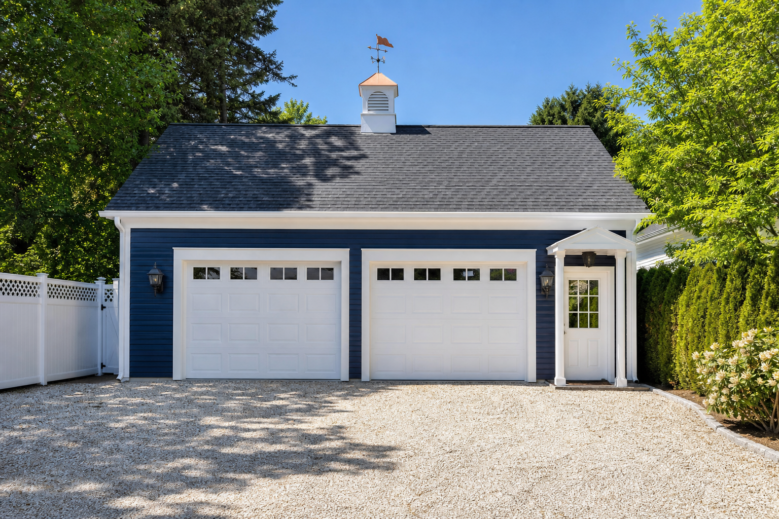 Navy blue detached garage with white trim cupola coach lanterns and gravel driveway