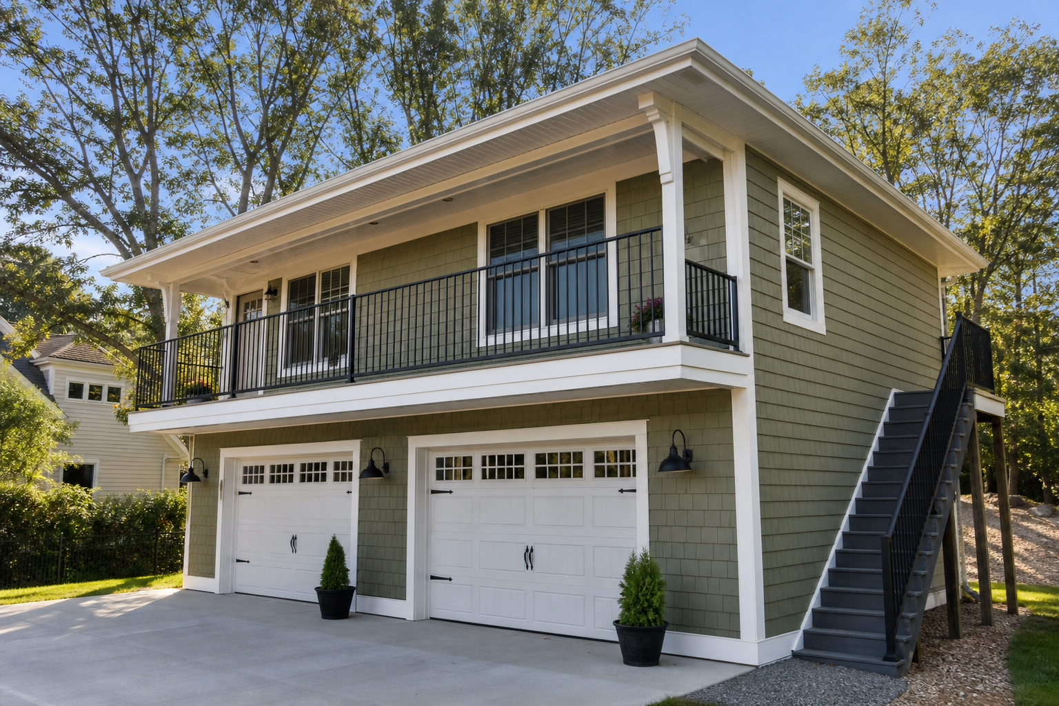 Two-story detached garage apartment with sage green upper level balcony and exterior staircase
