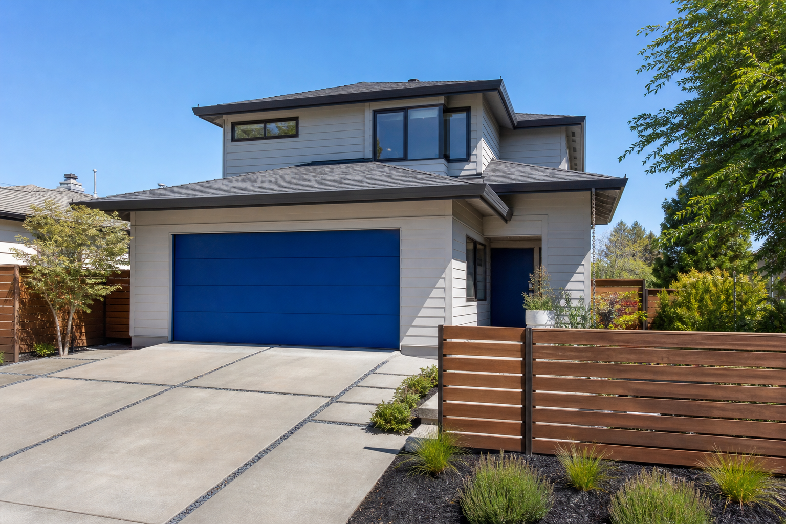 Saturated cobalt blue flush-panel garage door on a gray contemporary two-story home
