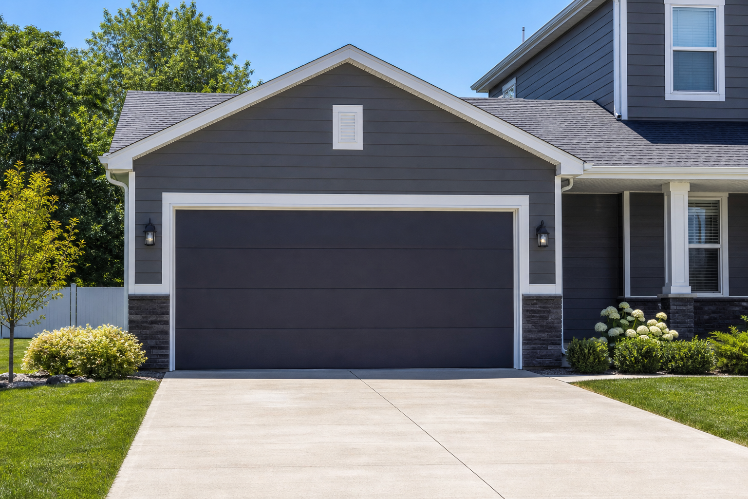 Two-car garage door painted deep charcoal gray with white trim on suburban home
