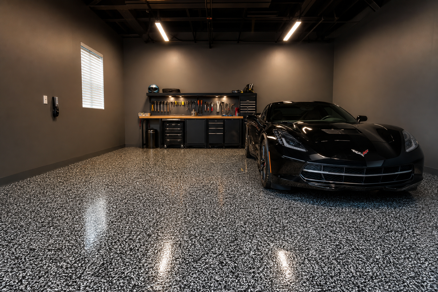 One-car garage with black and silver vinyl flake epoxy floor under industrial overhead lighting