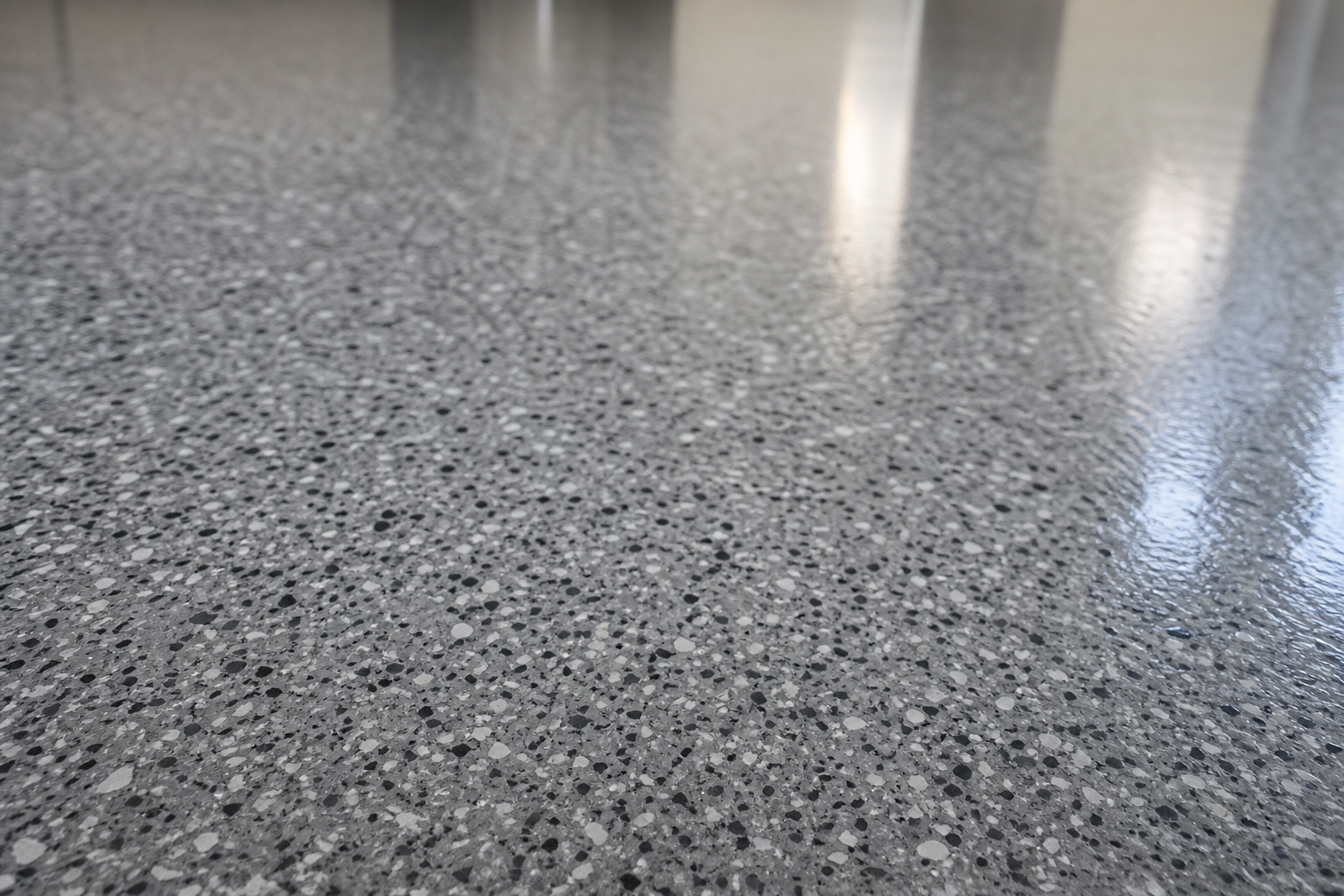 Close-up of granite-style fine chip epoxy garage floor with charcoal gray and white speckled finish