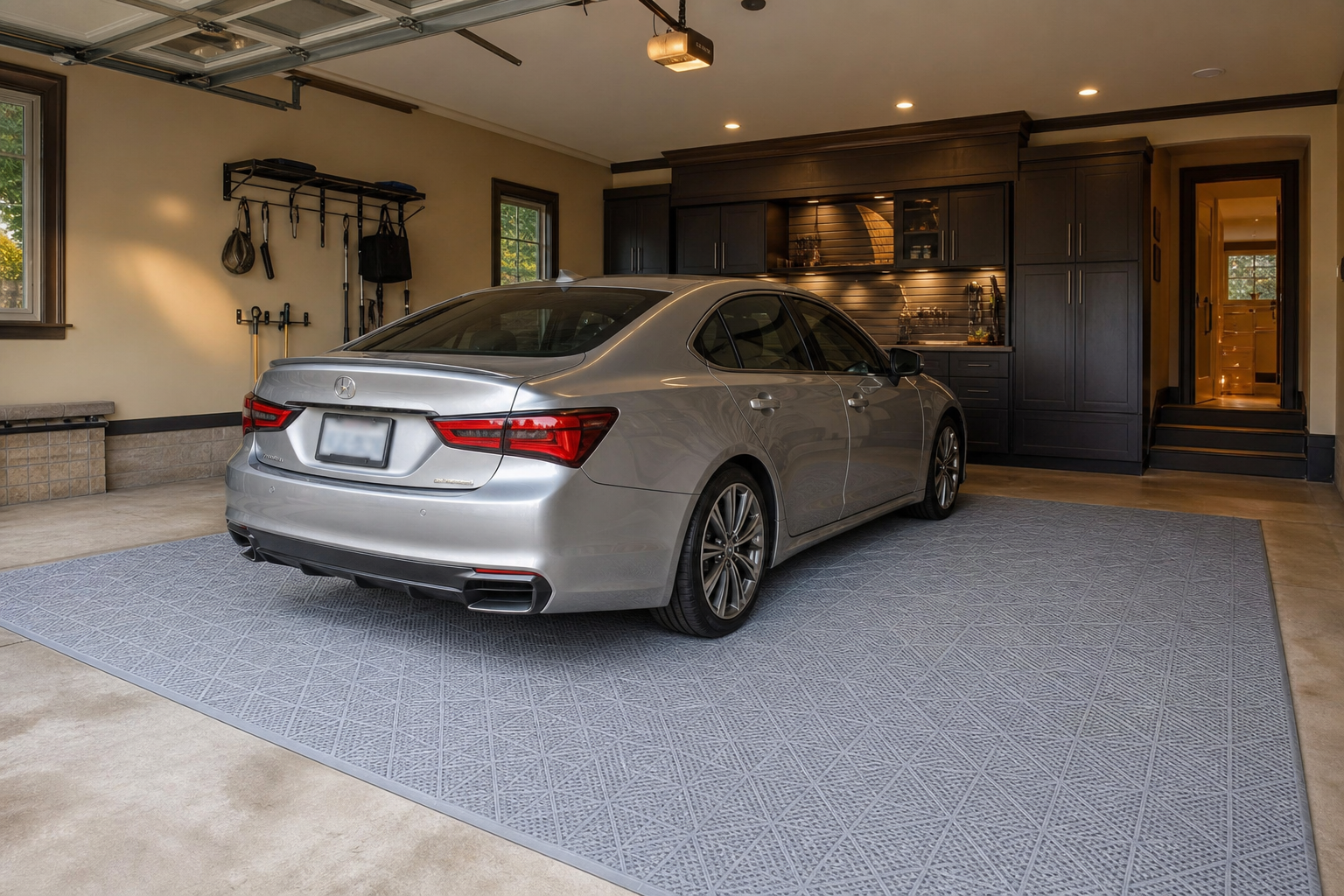 Light gray geometric grid vinyl roll-out mat in center of a two-car garage under a silver sedan