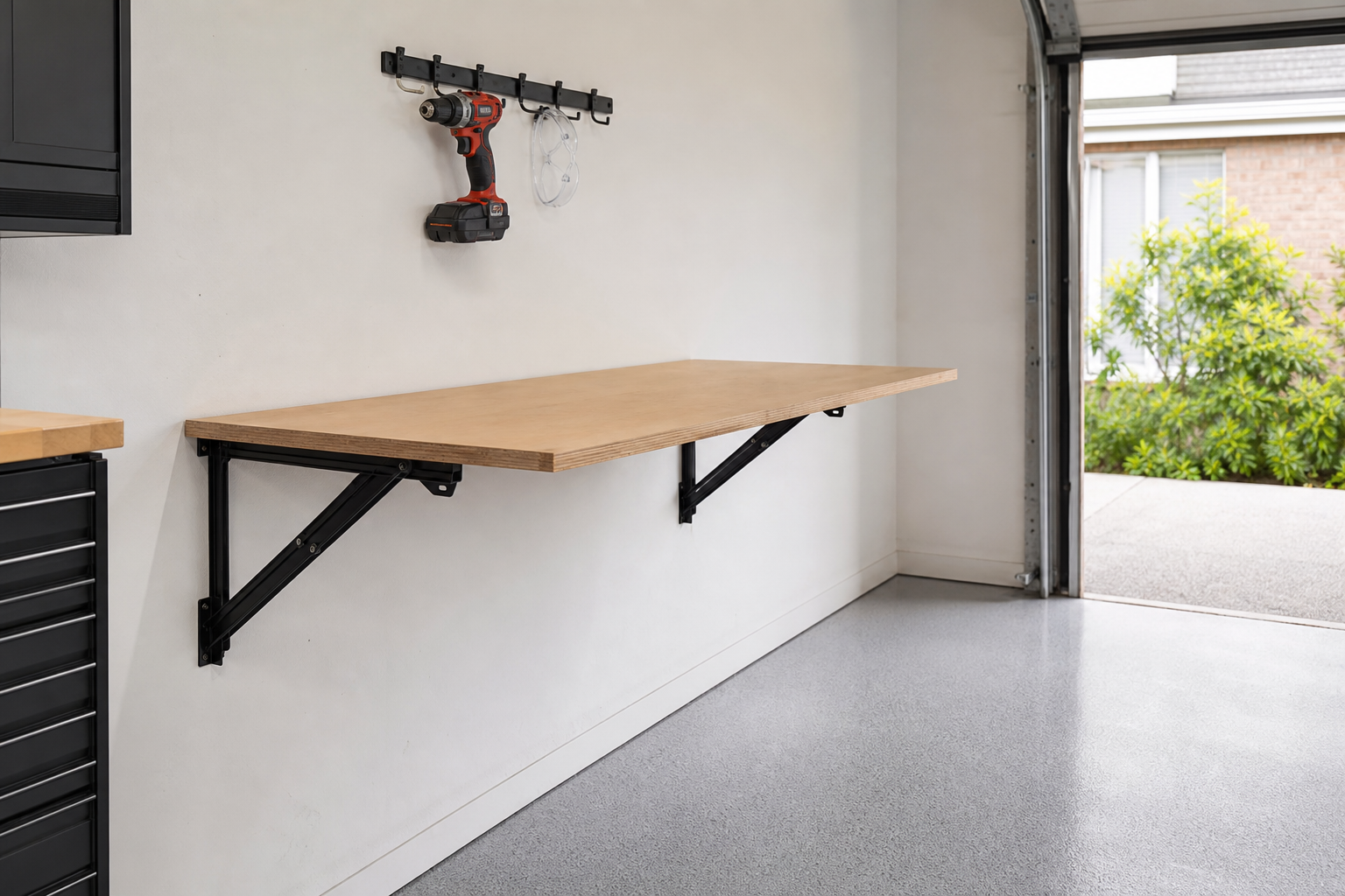 Simple fold-down birch plywood workbench open against white garage wall with black folding brackets