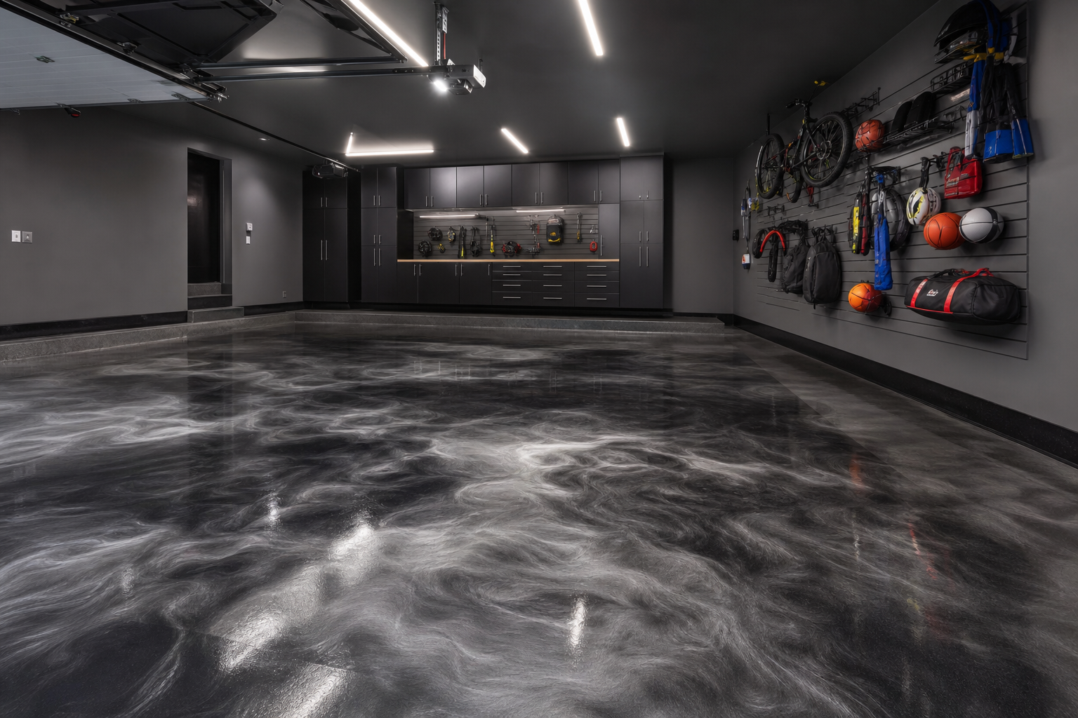 Dark graphite metallic epoxy garage floor with swirling smoke tones, black cabinets, and modern LED lighting