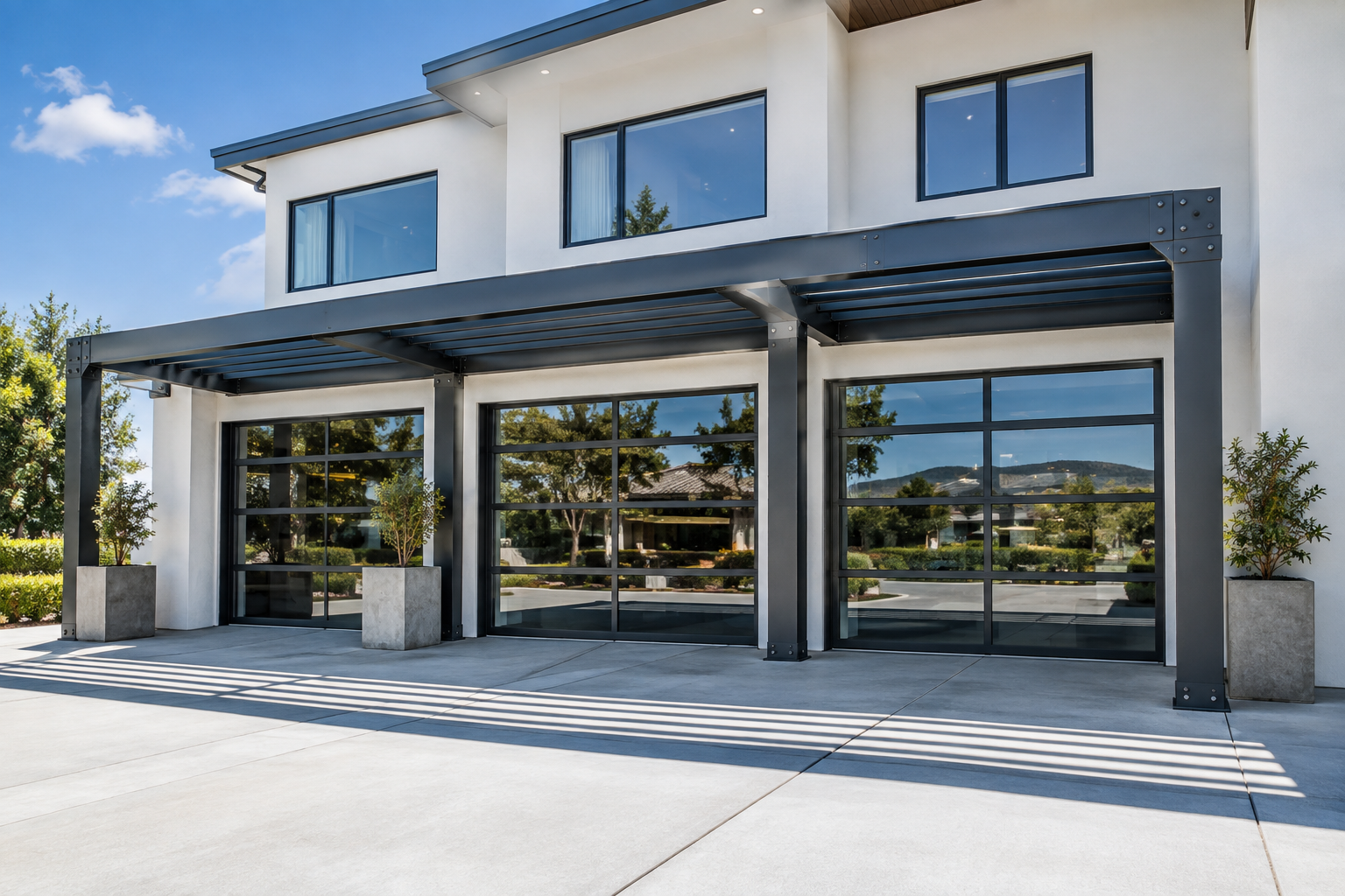 Graphite gray steel I-beam pergola spanning three full-view glass garage doors on a white contemporary home